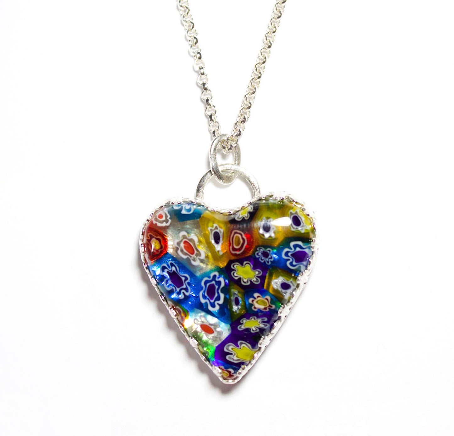 Heart shaped pendant made of millifiore glass. The heart is clear glass filled with glass tubes that are shaped like flowers and go from the front to the back of the heart. Multi color includes red, blue, yellow, and white. Surrounded by a heavy detailed gallery wire.