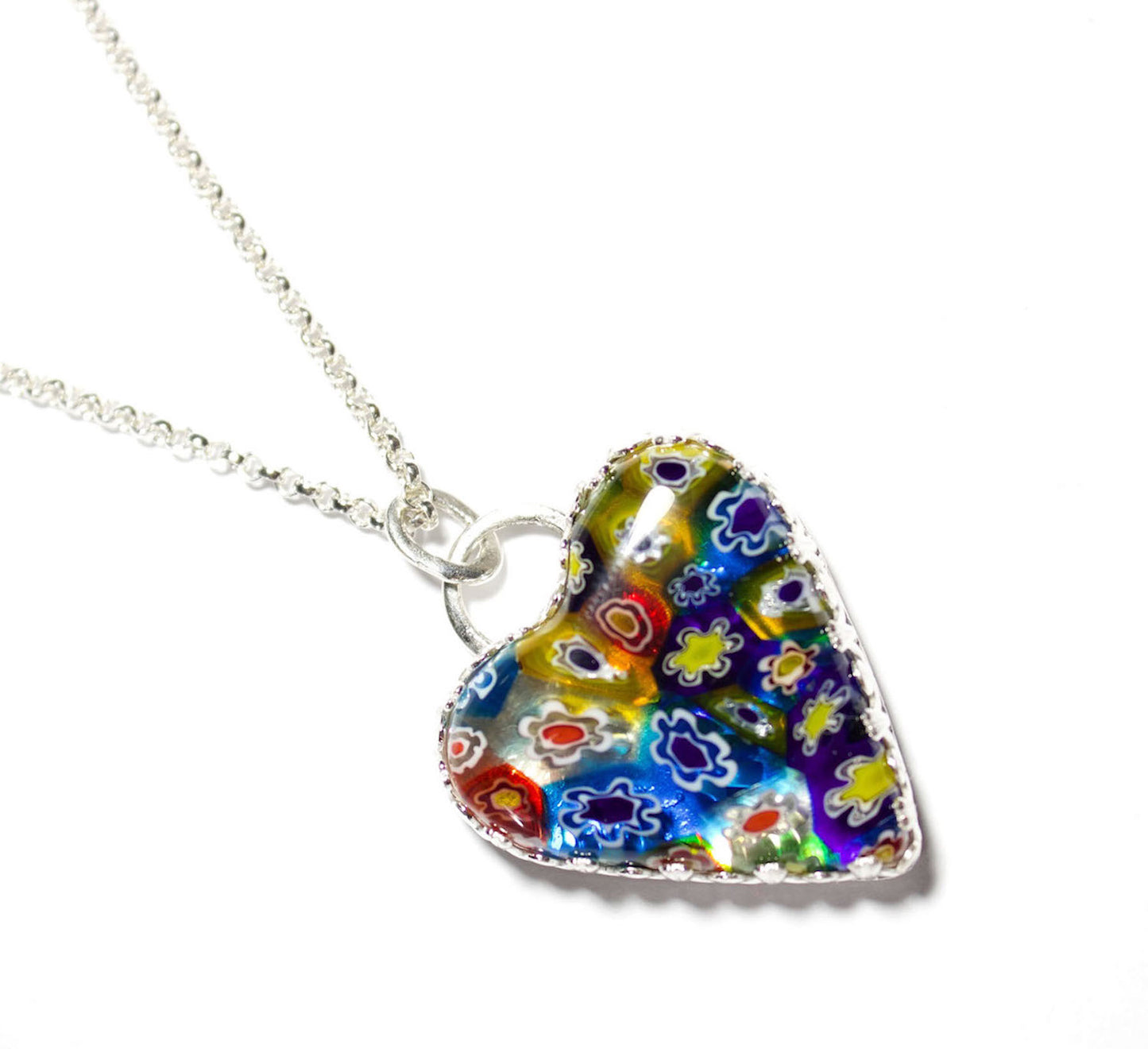 Heart shaped pendant made of millifiore glass. The heart is clear glass filled with glass tubes that are shaped like flowers and go from the front to the back of the heart. Multi color includes red, blue, yellow, and white. Surrounded by a heavy detailed gallery wire.