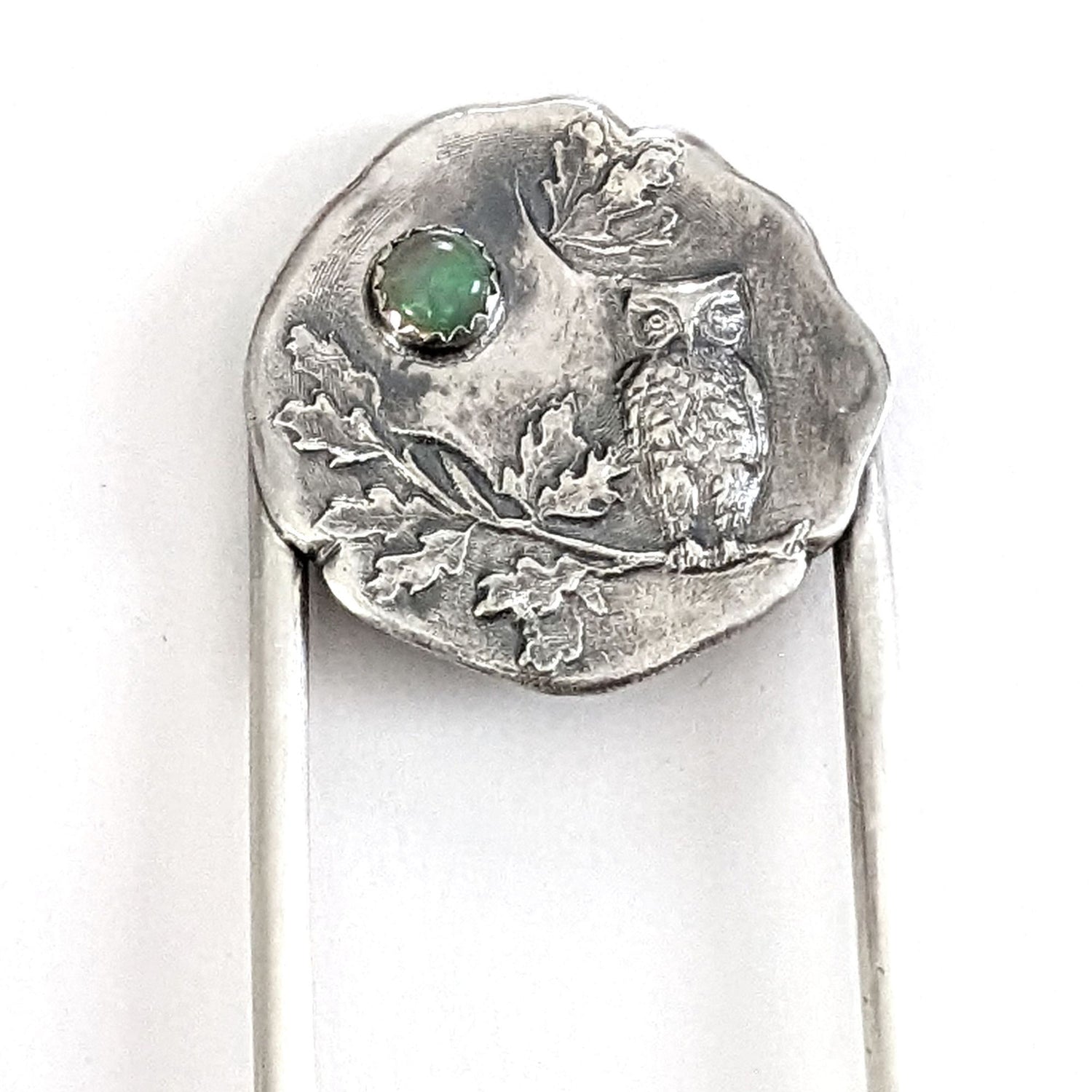Sterling silver hair fork. The design at the top of the hair fork is a round sterling silver piece with a 3 dimensional design of an owl sitting on a tree branch. The branch has leaves, oak perhaps. Above the leaves there is a white opal gemstone to represent the moon. 