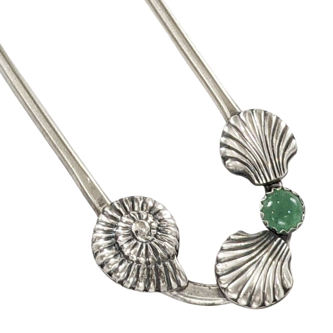 Sterling silver hair fork with three seashells and a green aventurine gemstone. Two of the seashells are scallop shaped and one is like a nautilus or ammonite.