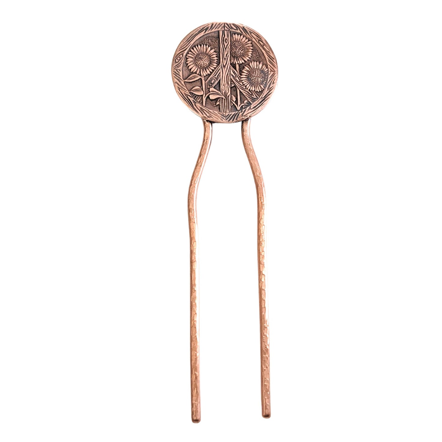 Copper hair fork with a large round design at top of sunflowers and a peace sign. The peace sign has a wood texture. Three sunflowers grow through the wood sign. There's a lot of detail - veins on the leaves, you can see the sunflower seeds and petals. On a copper fork with a hammered finish. This picture also shows the full length of the fork.