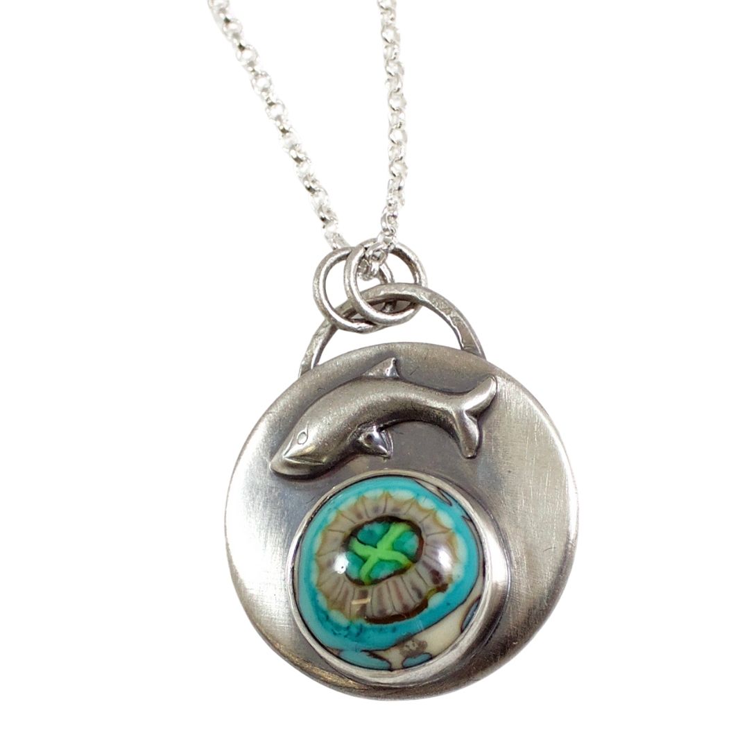 Handmade sterling silver pendant with a gray and aqua stone that looks like a sea anemone. Above the stone is a raised breaching whale design.