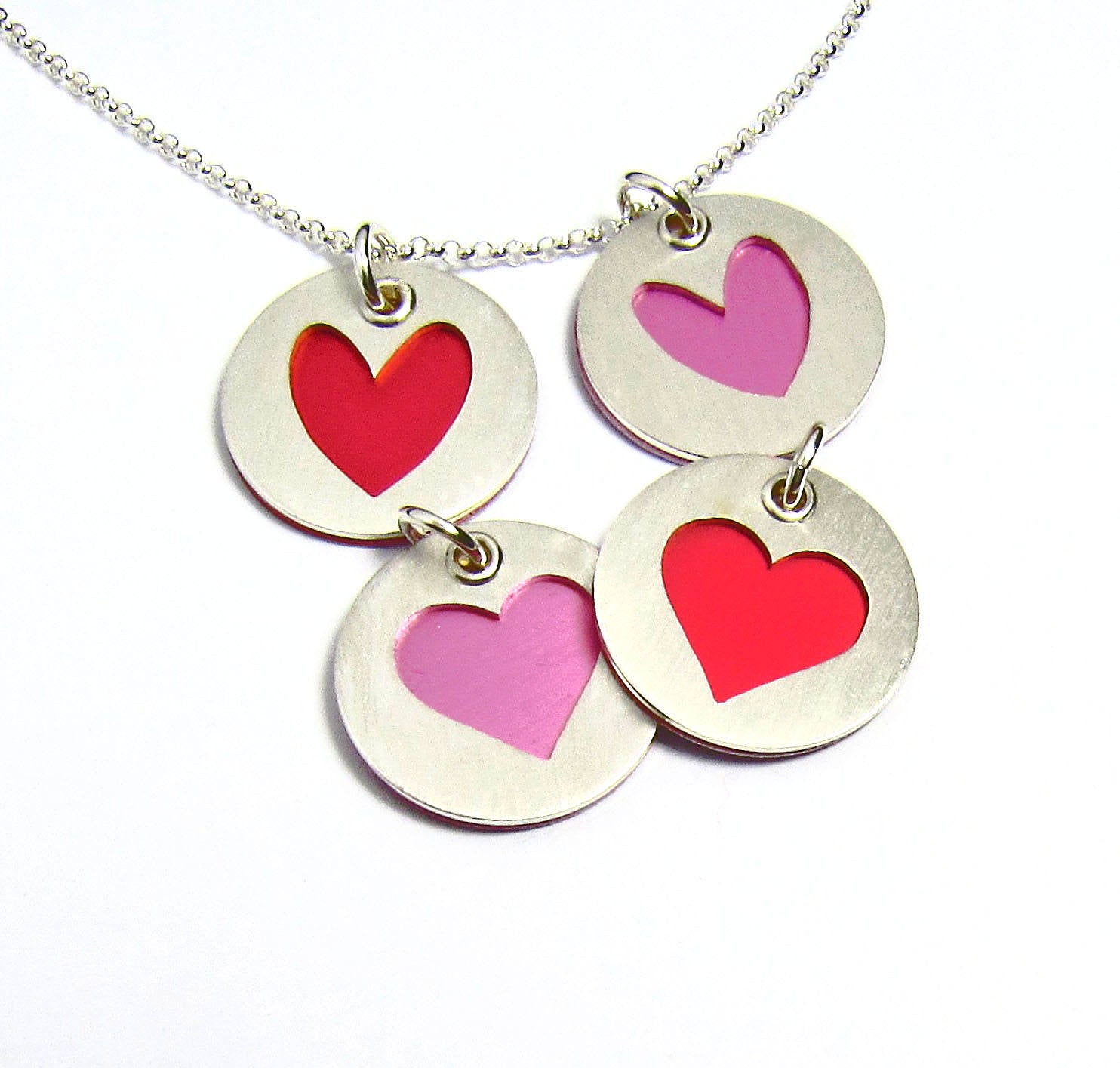 Collection of sterling silver heart charms for bracelets and necklaces. Shown in pink and red
