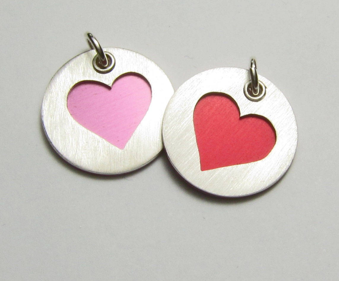 Collection of sterling silver heart charms for bracelets and necklaces. Shown in pink and red.