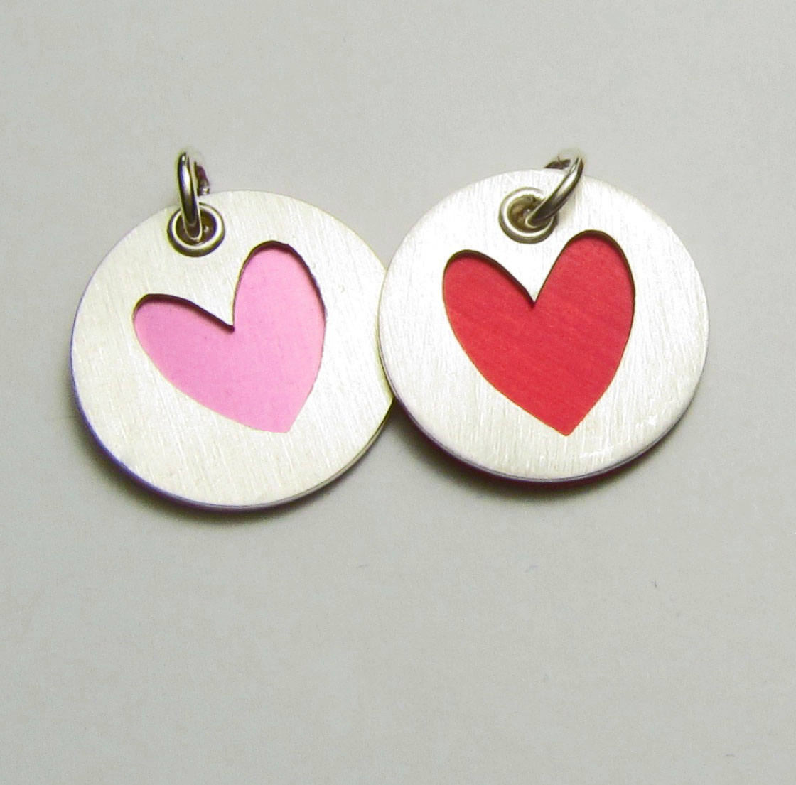 Collection of sterling silver heart charms for bracelets and necklaces. Shown in pink and red