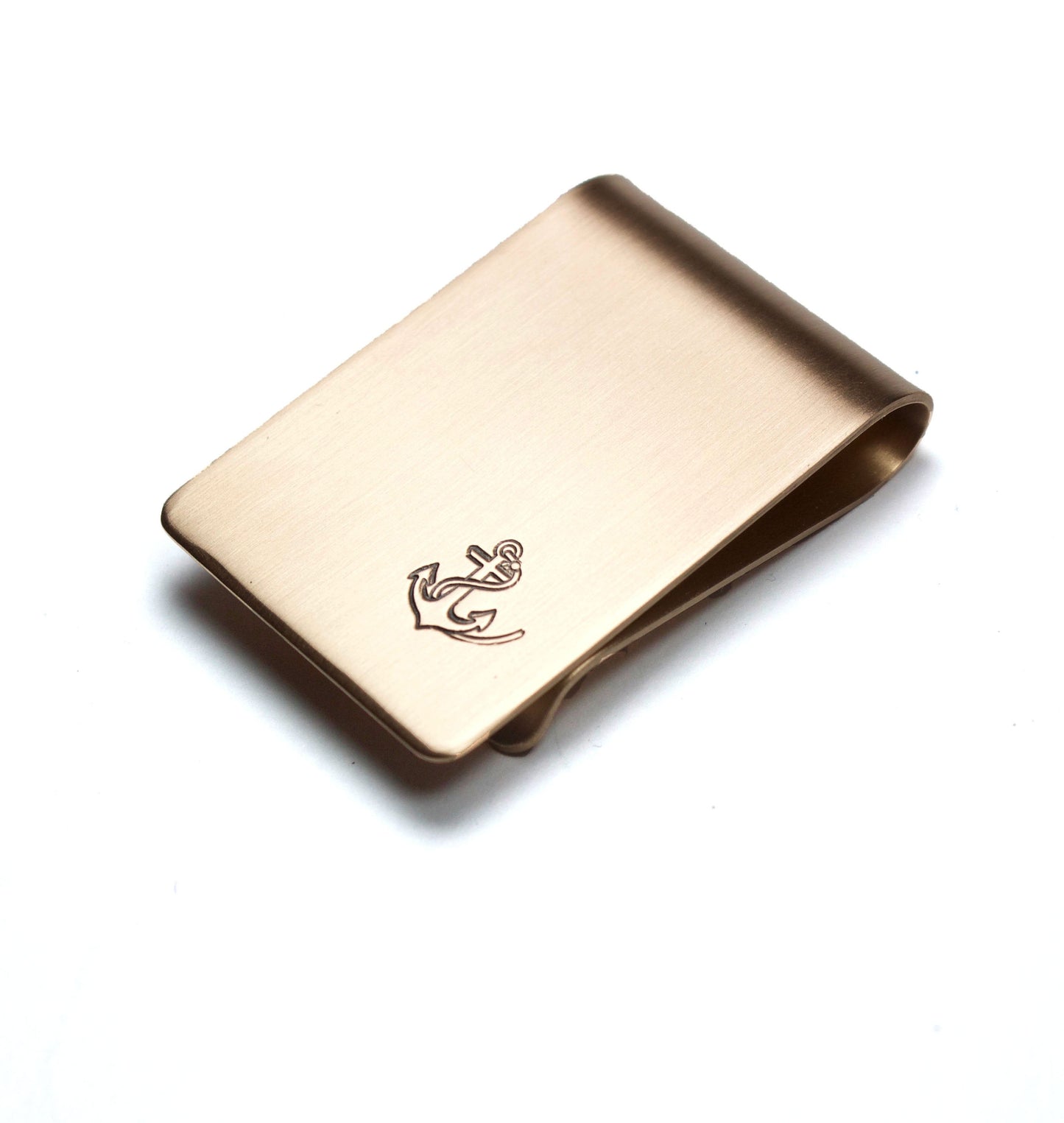 Anchor and Rope Money Clip. A small money clip with a stamped image of a boat anchor wrapped in a length of rope. The stamped design is darkened (oxidized). The money clip is shown in bronze metal.