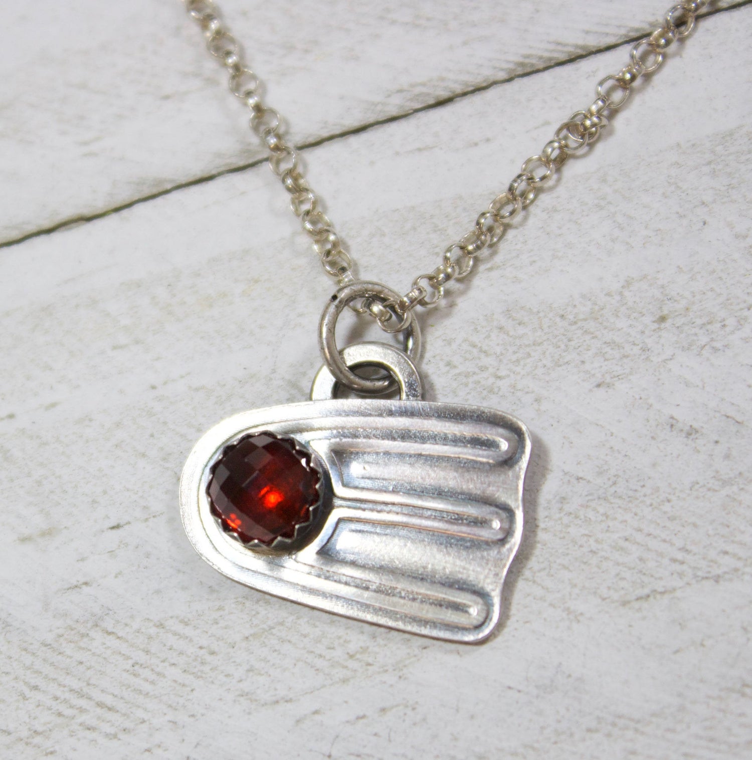 Comet shaped sterling silver pendant with a rose cut red garnet
