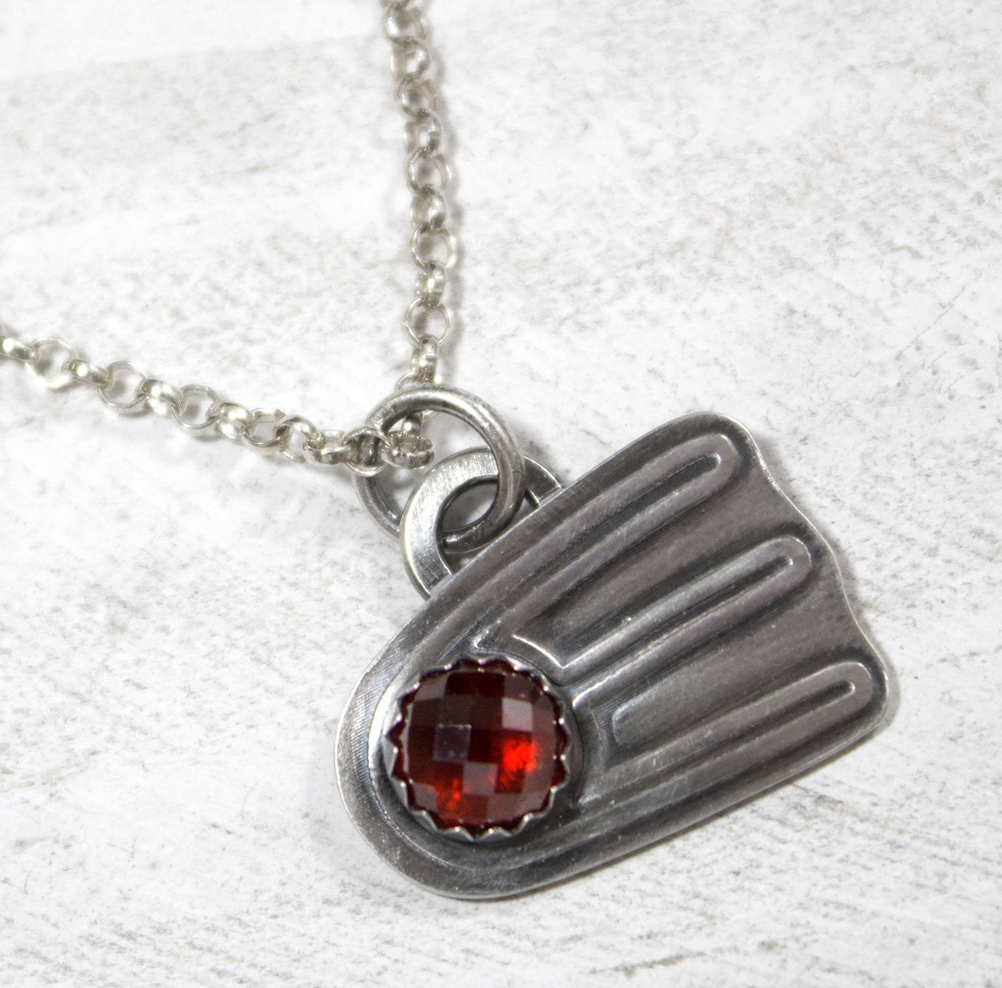 Comet shaped sterling silver pendant with a rose cut red garnet