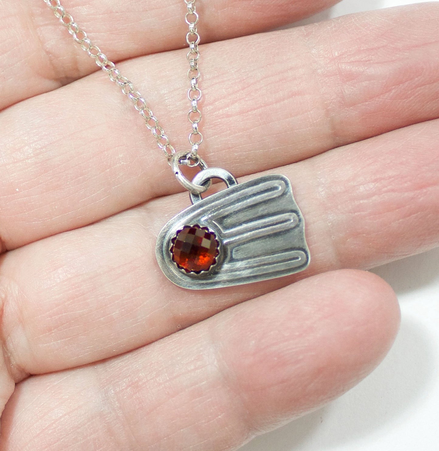 Comet shaped sterling silver pendant with a rose cut red garnet